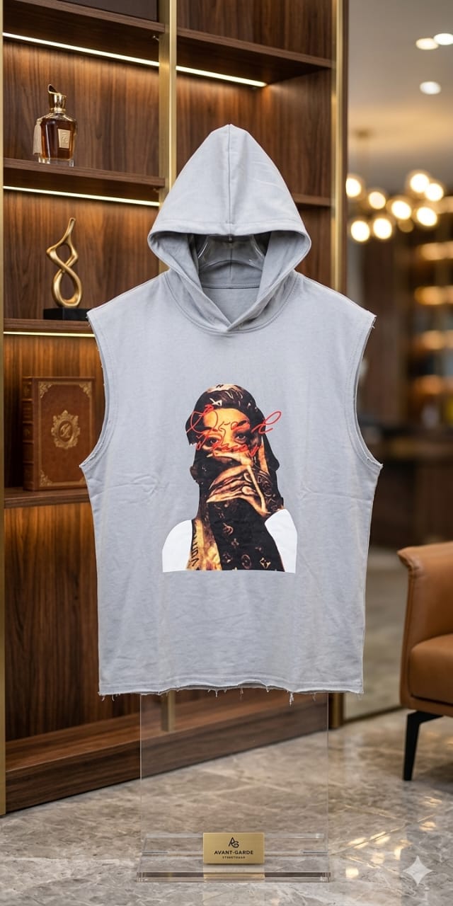 Cool oversized sleeveless hoodie tank in washed gray featuring a bold front graphic print of a masked figure wearing a monogram bandana with red script overlay text. Raw frayed hem at the bottom for a distressed edgy finish. Pullover hood with no drawstring and wide armhole cutouts for a relaxed muscle fit. Lightweight fabric perfect for summer streetwear, gym wear, layering, or casual statement styling.