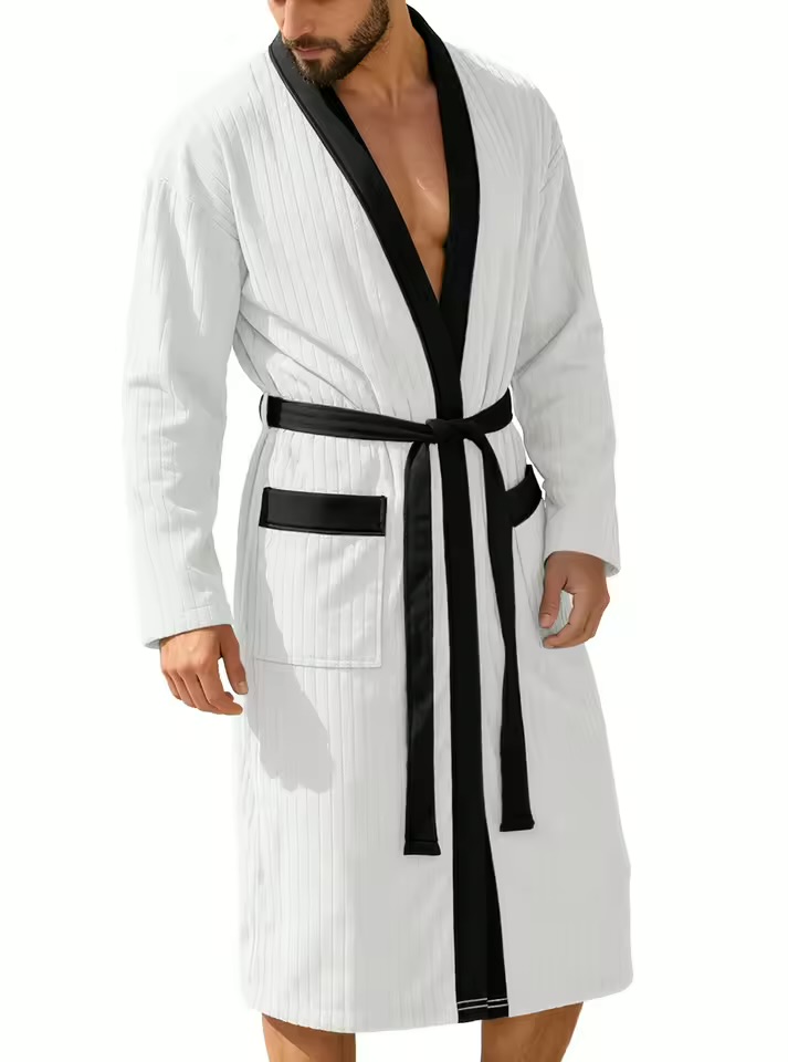 Unwind in spa-like luxury with this striking crisp white bathrobe. The clean white ribbed body stands out against the solid black lapel lining and pocket trim, creating a bold, high-contrast aesthetic that keeps you looking sharp even on casual mornings.
