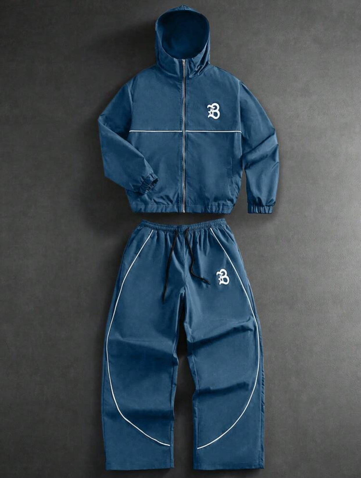Deep Slate Blue Weather-Resistant Functional Hooded Windbreaker Utility Jacket and Relaxed Baggy Track Pants Athleisure Tracksuit Set Featuring Minimalist White Contour Piping Accents and Stylized Old English Varsity Letter "B" Monogram Logo