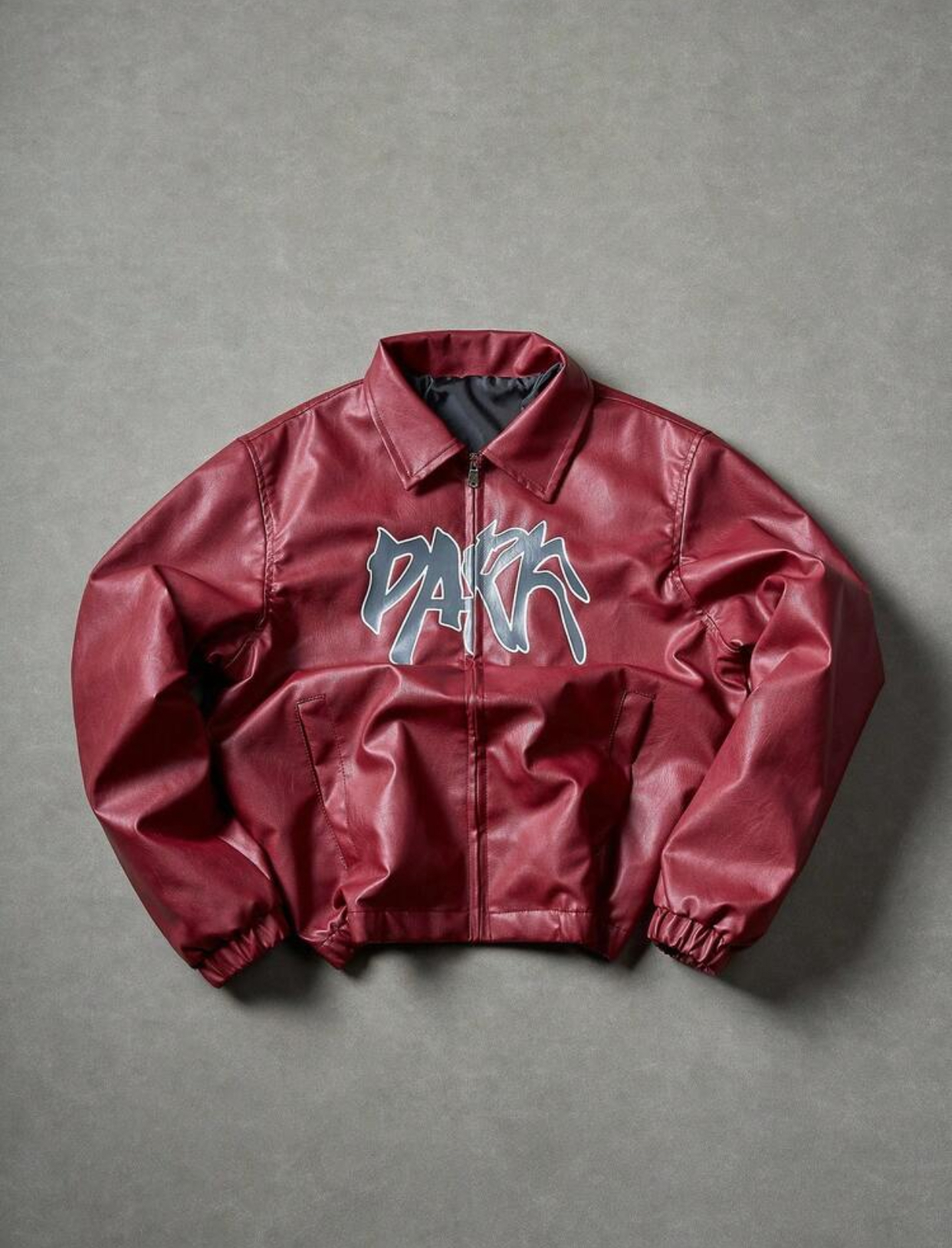 Contemporary Cream-Ivory Supple Faux-Leather Turn-Down Collar Streetwear Blouson Bomber Jacket Configured with Dual Front Slit Welt Pockets, Silver Zipper Hardware, and a Central Abstract Dark Slate Grey-Blue Graffiti "PARK" Bubble Script Graphic
