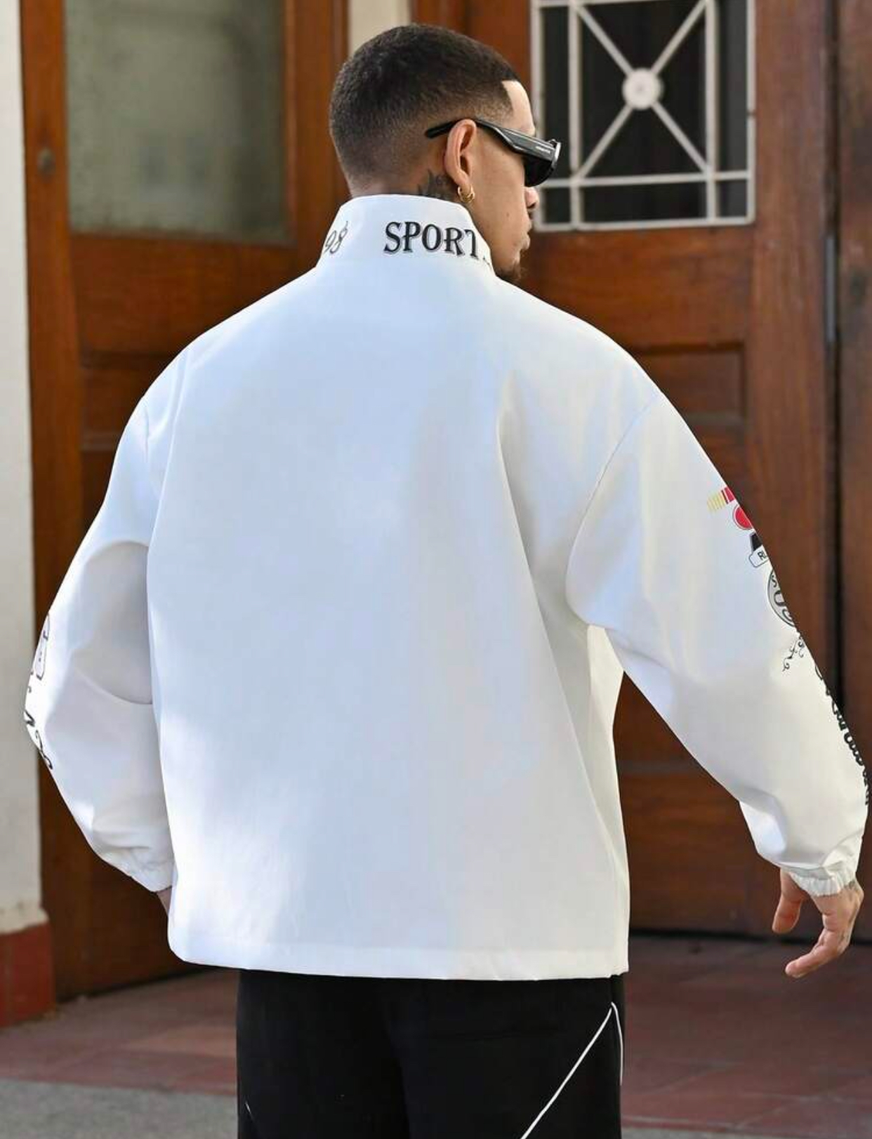 Retro Motorsport-Inspired White Windbreaker Racing Jacket Heavily Embellished with Multicolored Athletic Graphic Badges, High-Neck "SPORTS" Collar, and Large Curving "SPORTS REFUELING" Chest Typography 2