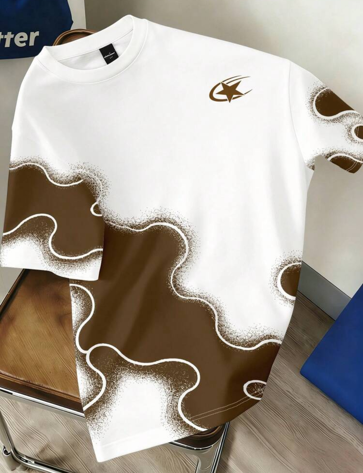 Modernist White Streetwear T-Shirt Embellished with an Earthy Chocolate Brown Liquid Amoeba Organic Pattern Featuring Distressed Airbrushed Stipple Edges and a Miniature Metallic Gold Comet Star Logo